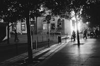 日落时分，城市街道呈现黑白场景，剪影般的行人与戏剧性的阴影交织其间