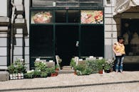 一家充满活力的城市花店外，一位女子站在植物和花盆的环绕之中