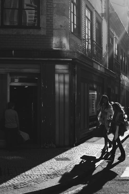 Grayscale Photo Of Two Women Walking Near Building