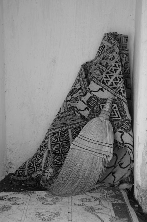Free A black and white still life of a broom and rug in a simple home corner. Stock Photo