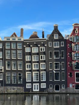 Quaint Amsterdam canal houses with unique facades reflecting in the calm water.