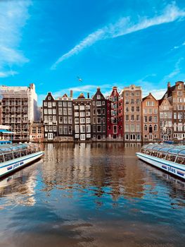 Charming view of historic canal houses in Amsterdam during a clear day, reflecting in the water.