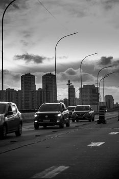Monochrome city traffic with skyscrapers in the background.