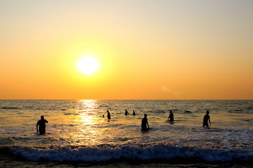 日没時にビーチにいる人々の写真