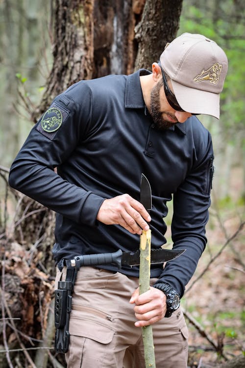 Man Crafting a Spear in a Forest