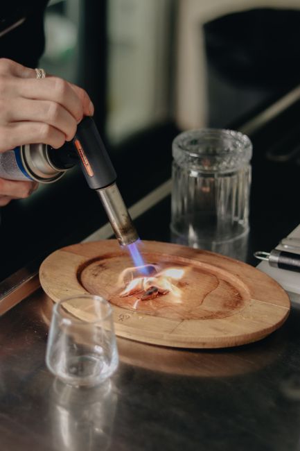 A shot glass of amaretto and 151 rum burning with a blue flame, held over a mug of beer ready for the drop.