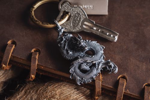 Free Detailed metal dragon keychain with a textured finish lying on a rustic leather notebook. Stock Photo