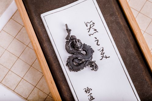 Free Close-up of a detailed metal dragon keychain resting on traditional Chinese calligraphy paper. Stock Photo