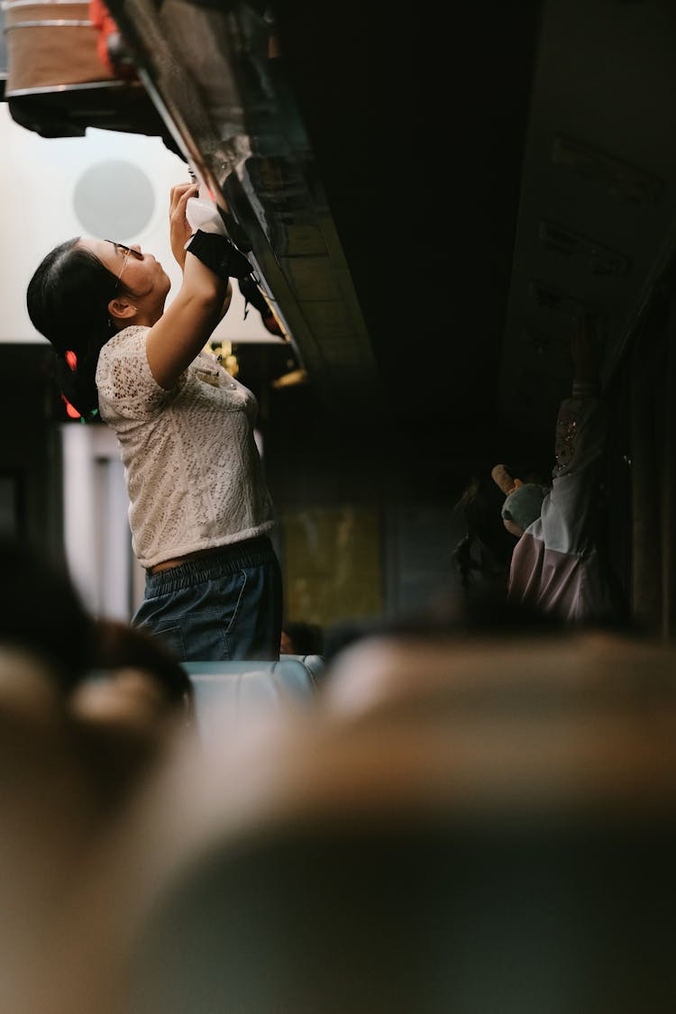 Woman Using Overhead Locker