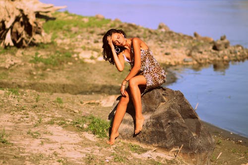 Free Woman in Brown and Black Leopard Cami Dress Siting on Grey Rock during Daytime Stock Photo