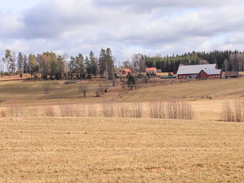 Free Beautiful rural farmland landscape with red barns and fields under a cloudy sky in early spring. Stock Photo