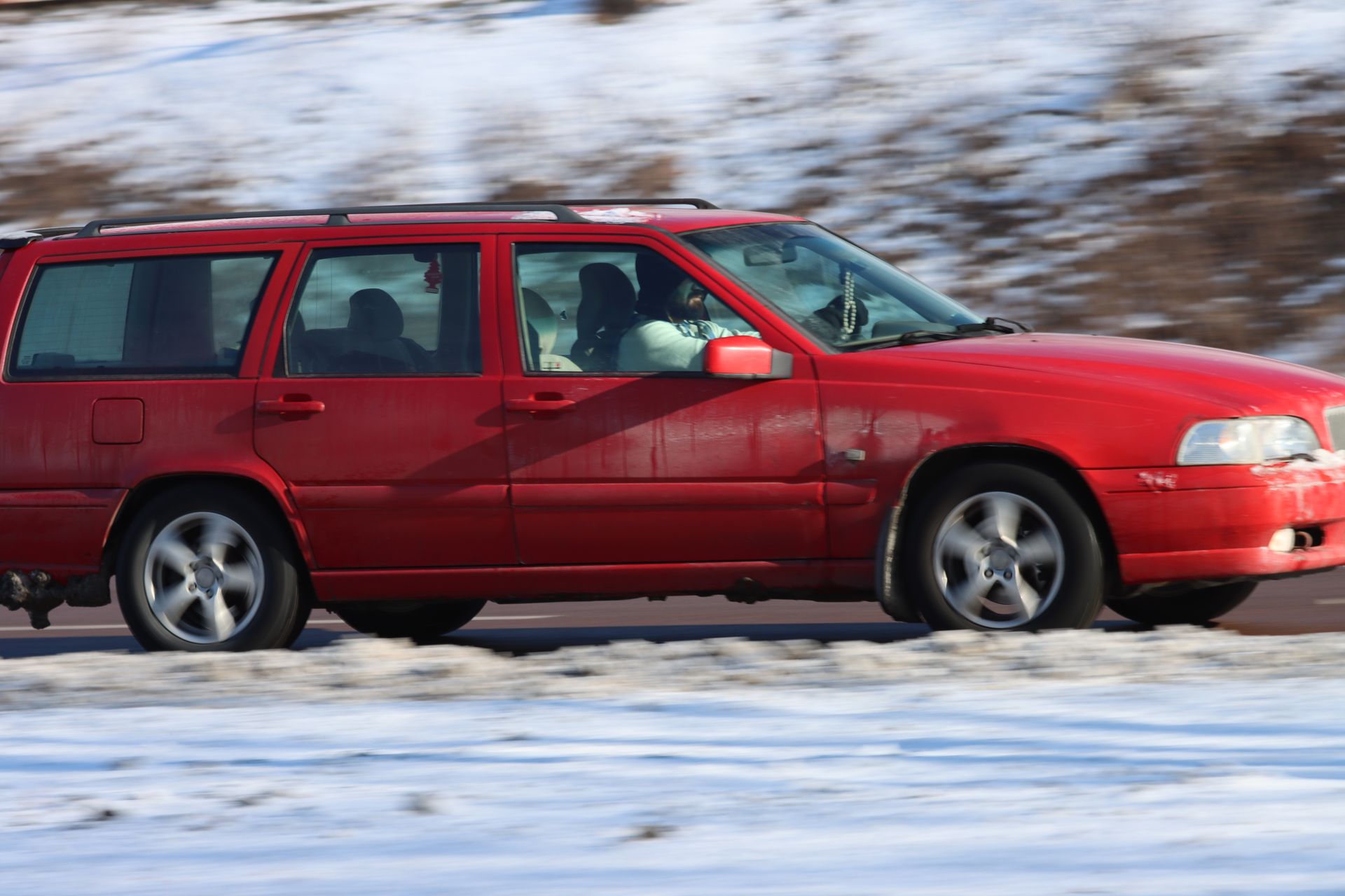 Rotes Auto unterwegs auf einer winterlichen Straße.