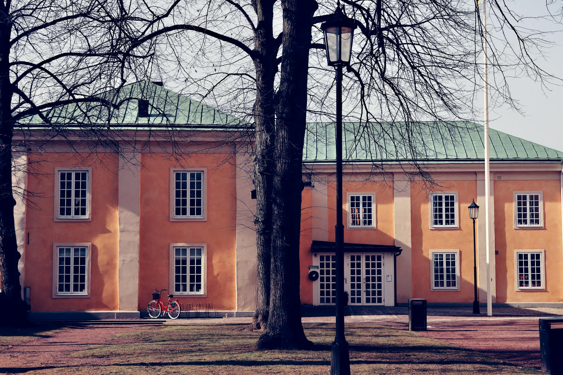 A vibrant orange building with green roof in Jönköping, Sweden, surrounded by trees.