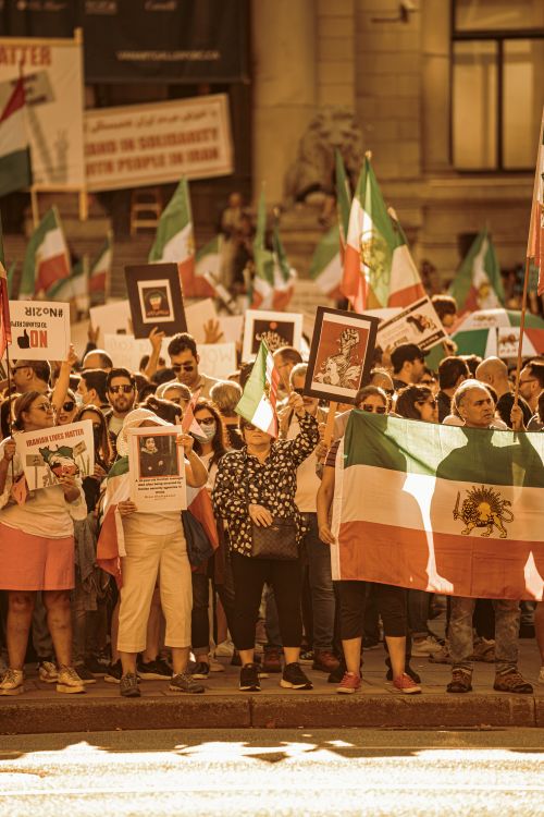 Free A diverse crowd participates in a protest in Vancouver, waving Iranian flags and holding signs. Stock Photo