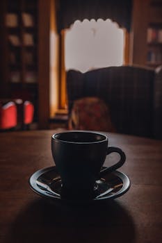 A moody indoor scene featuring a coffee cup on a table in a cozy setting.