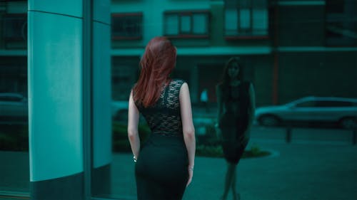 無料 建物の鏡の前で黒いレースのボディコンドレスの女性 写真素材