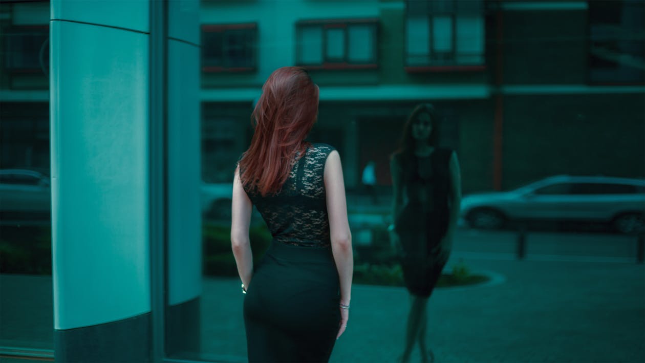 бесплатная Женщина в черном кружевном облегающем платье перед строительным зеркалом Стоковое фото