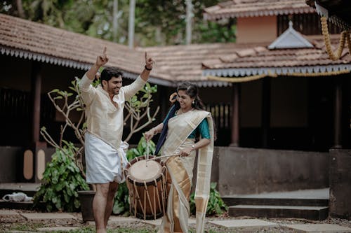 Laughing Couple in Traditional Clothing Standing with Drum