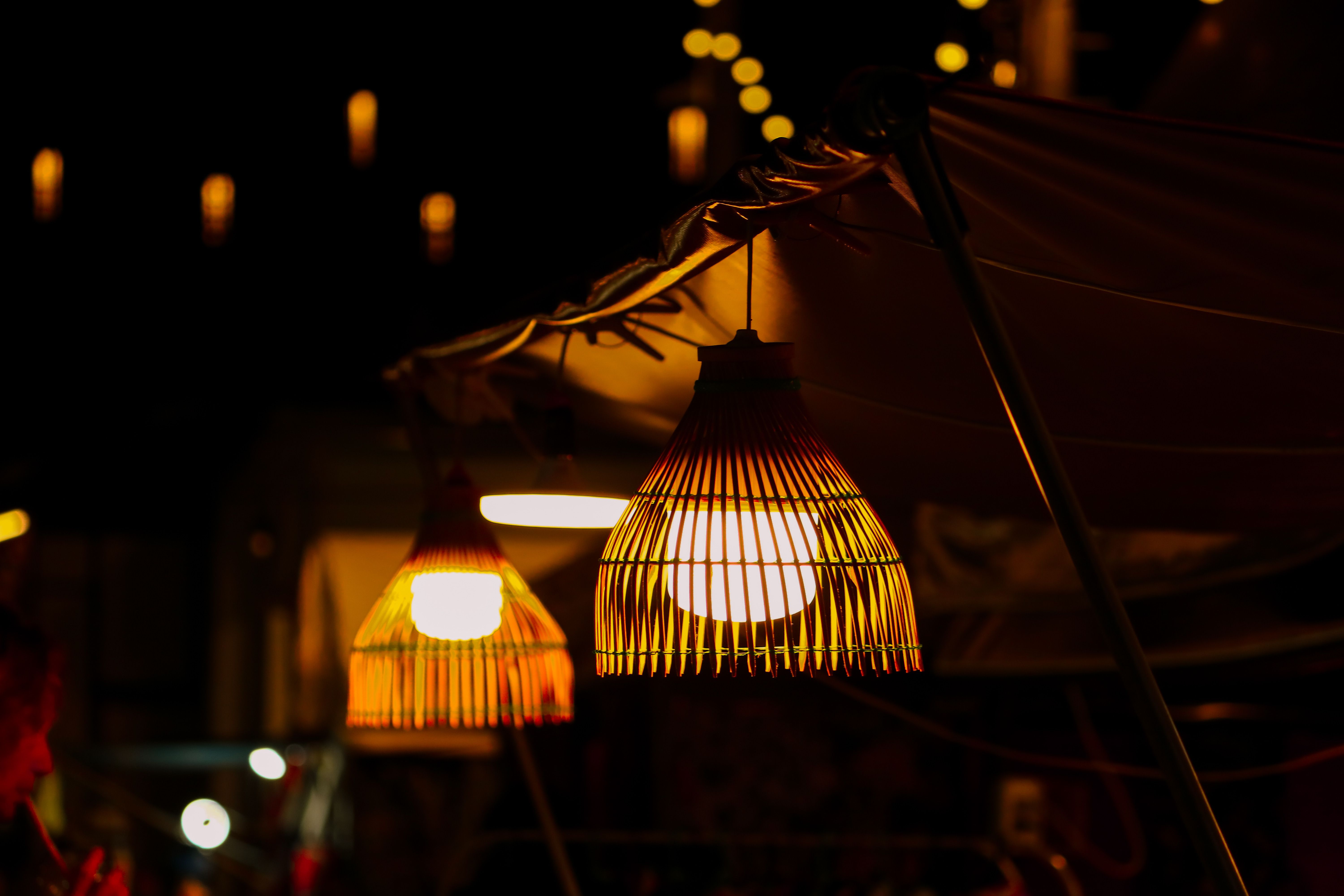 Warm light from woven lanterns at a night market, creating a cozy atmosphere.