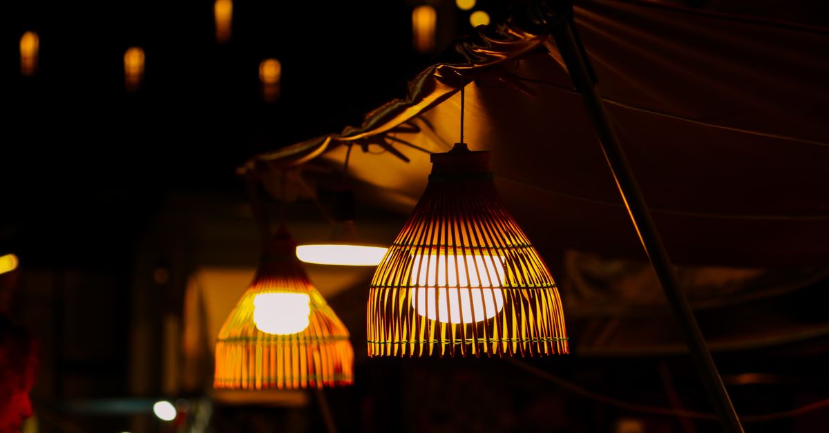 Warm light from woven lanterns at a night market, creating a cozy atmosphere.