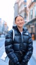 Young Woman in a Winter Jacket Standing on the Street in City and Smiling
