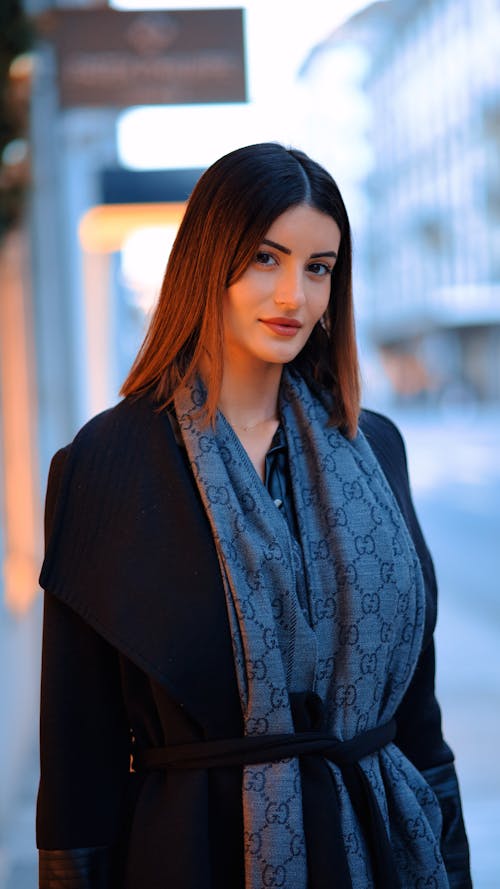 Elegant Woman in a Coat and Scarf Standing in City 