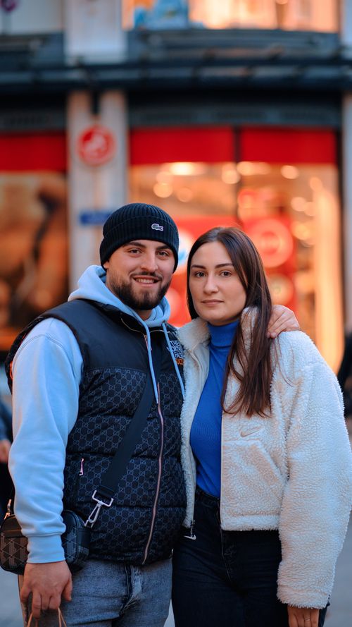 Free Smiling couple posing together on a city street at dusk, enjoying an urban atmosphere. Stock Photo