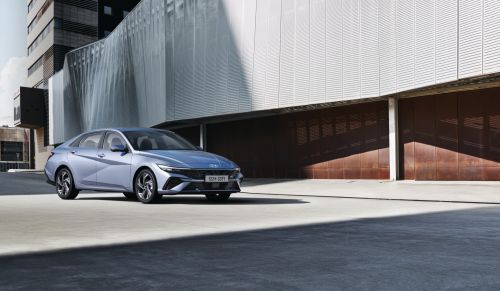 Free A sleek modern sedan parked in front of a contemporary building in an urban setting. Stock Photo