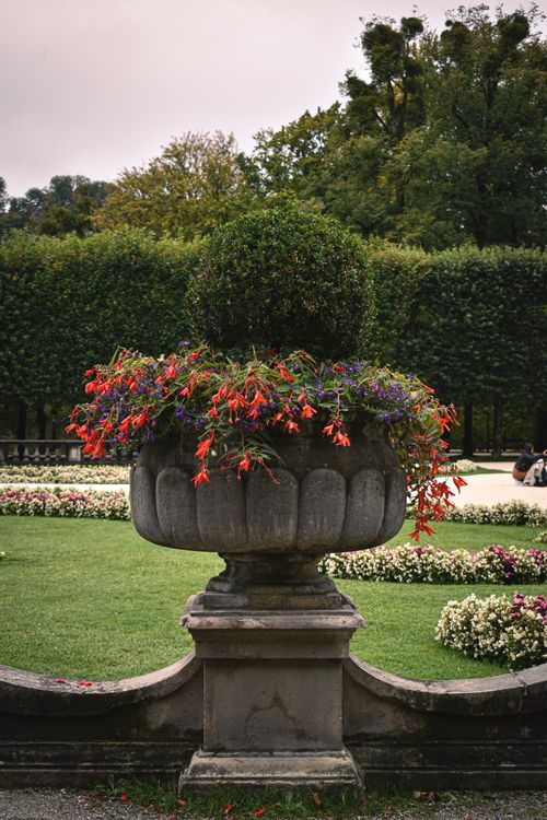 Free A classic stone planter filled with vibrant flowers in a lush garden setting. Stock Photo