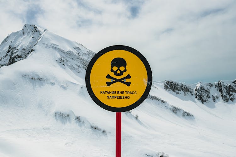 Warning Sign With Jolly Roger In Snowed Mountains