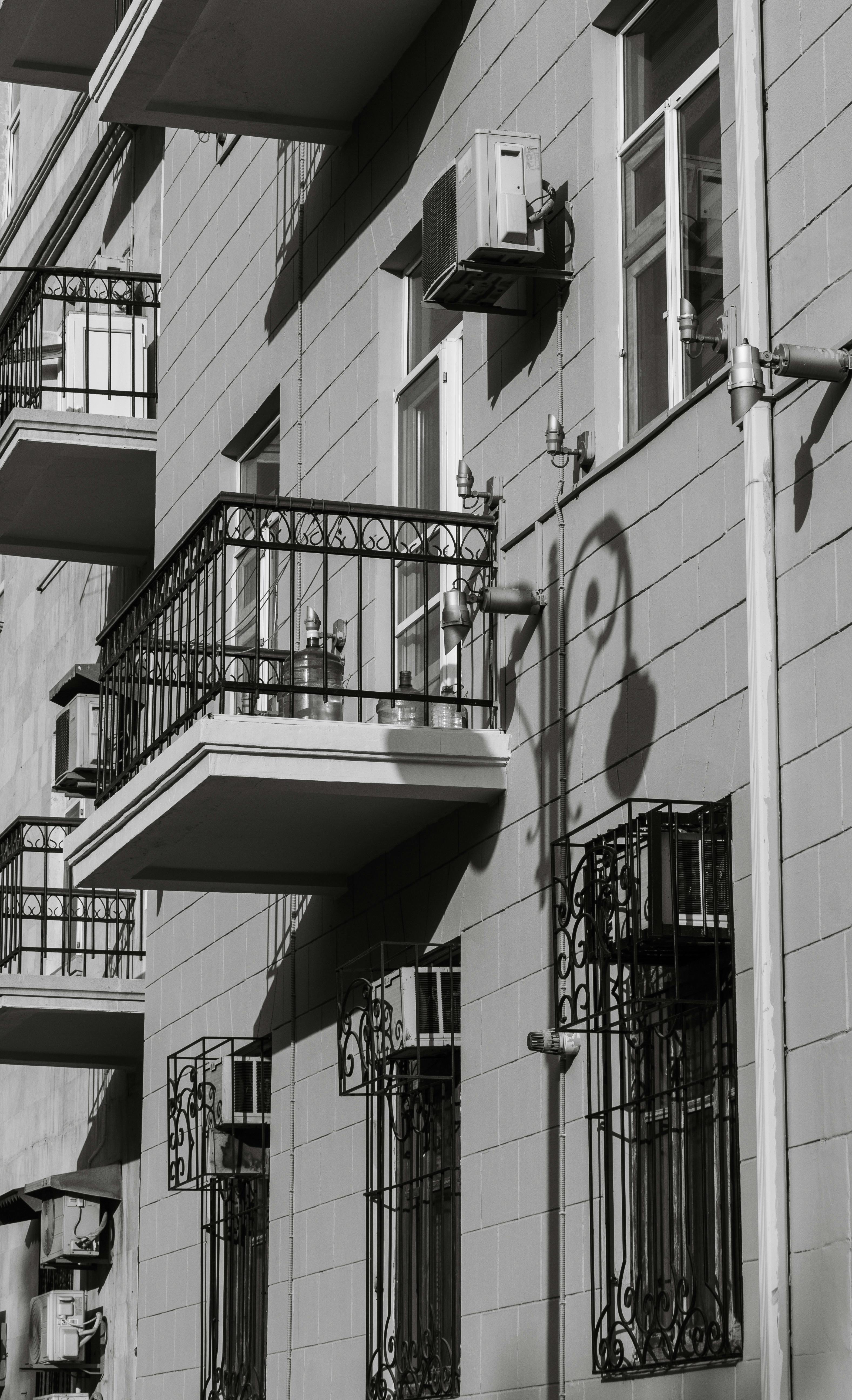 Black and white photo of a residential building facade with balconies and shadows creating urban depth.
