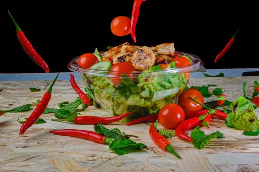 Colorful salad with grilled chicken, tomatoes, and chili peppers, shot creatively for a vibrant look.