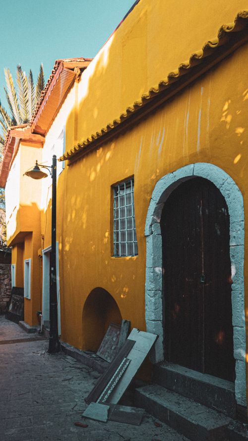 Free A vibrant yellow building facade on a narrow urban street with classic architecture. Stock Photo