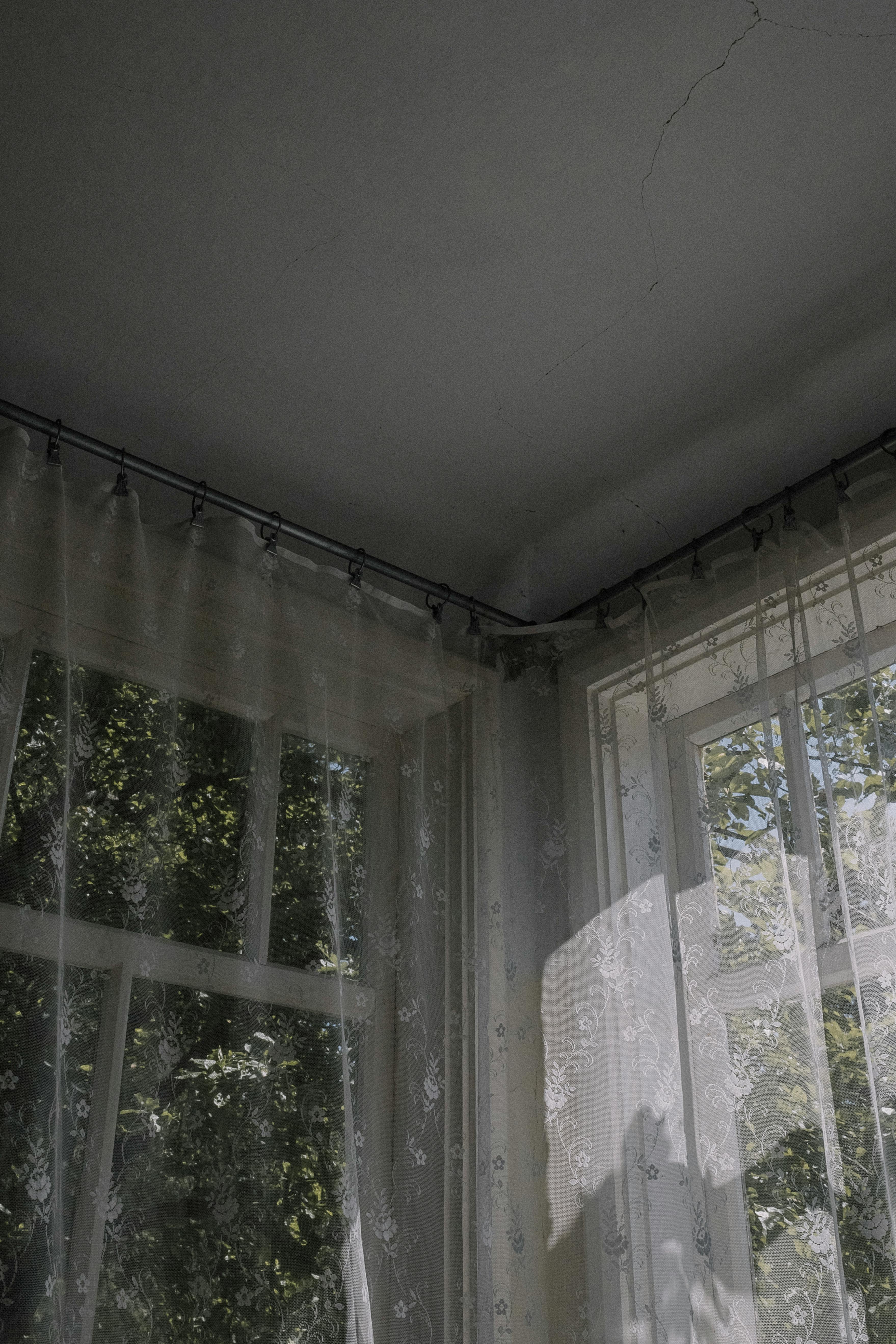 Free Sunlight streaming through lace curtains with nature visible outside the window. Stock Photo