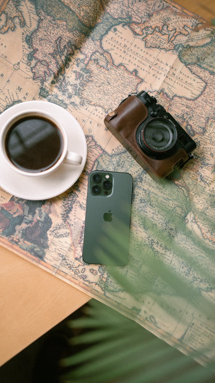 Photo Of Coffee, Analog Camera And Smartphone Spread Out On A Map