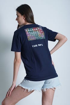 Woman in denim shorts and graphic t-shirt posing against a white background.