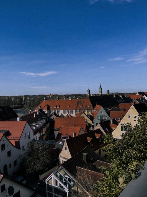 Free Scenic aerial view of a European town with red-roofed houses and clear blue sky. Stock Photo
