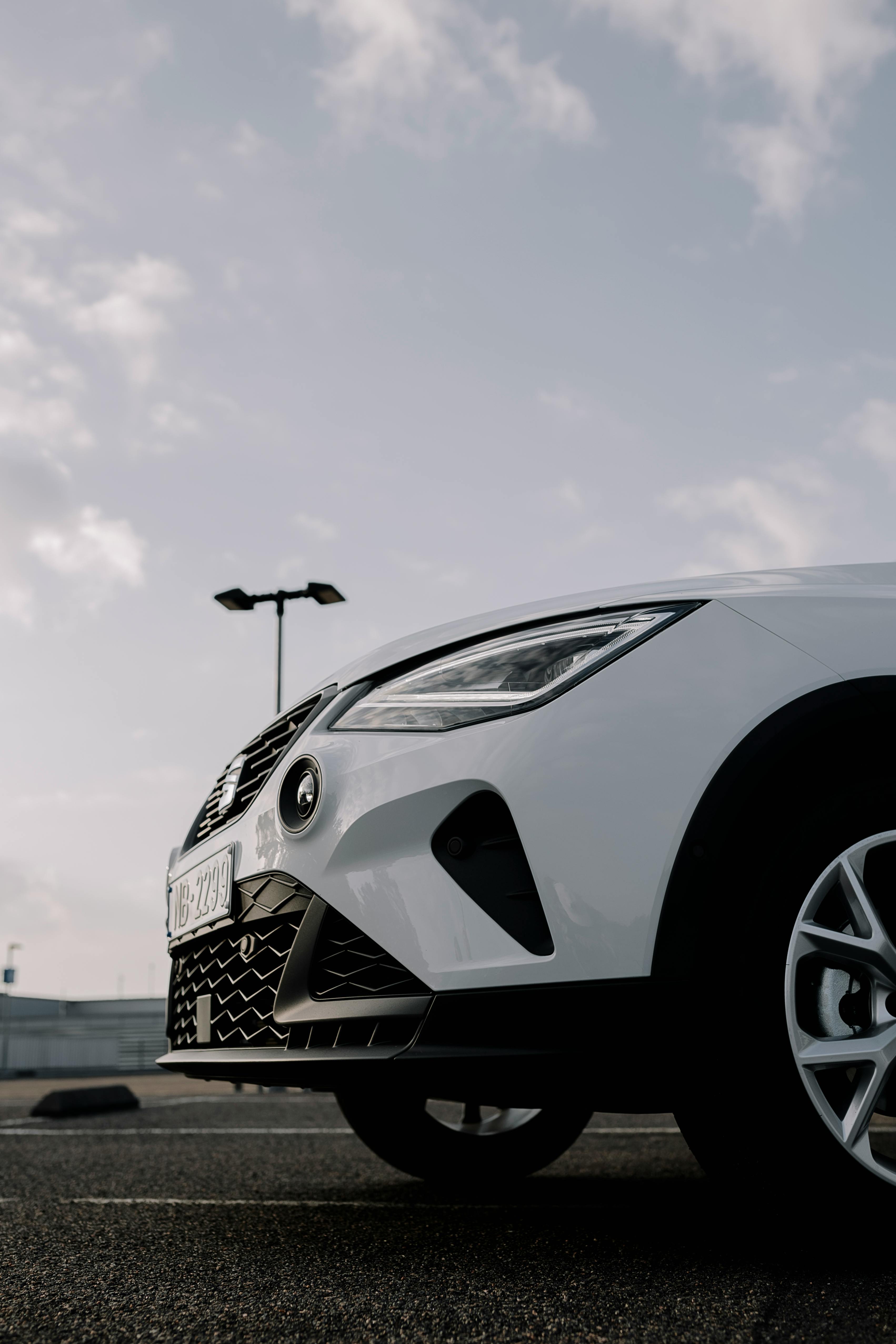 Free Dynamic angle shot of a white car in an outdoor parking lot with clear skies. Stock Photo