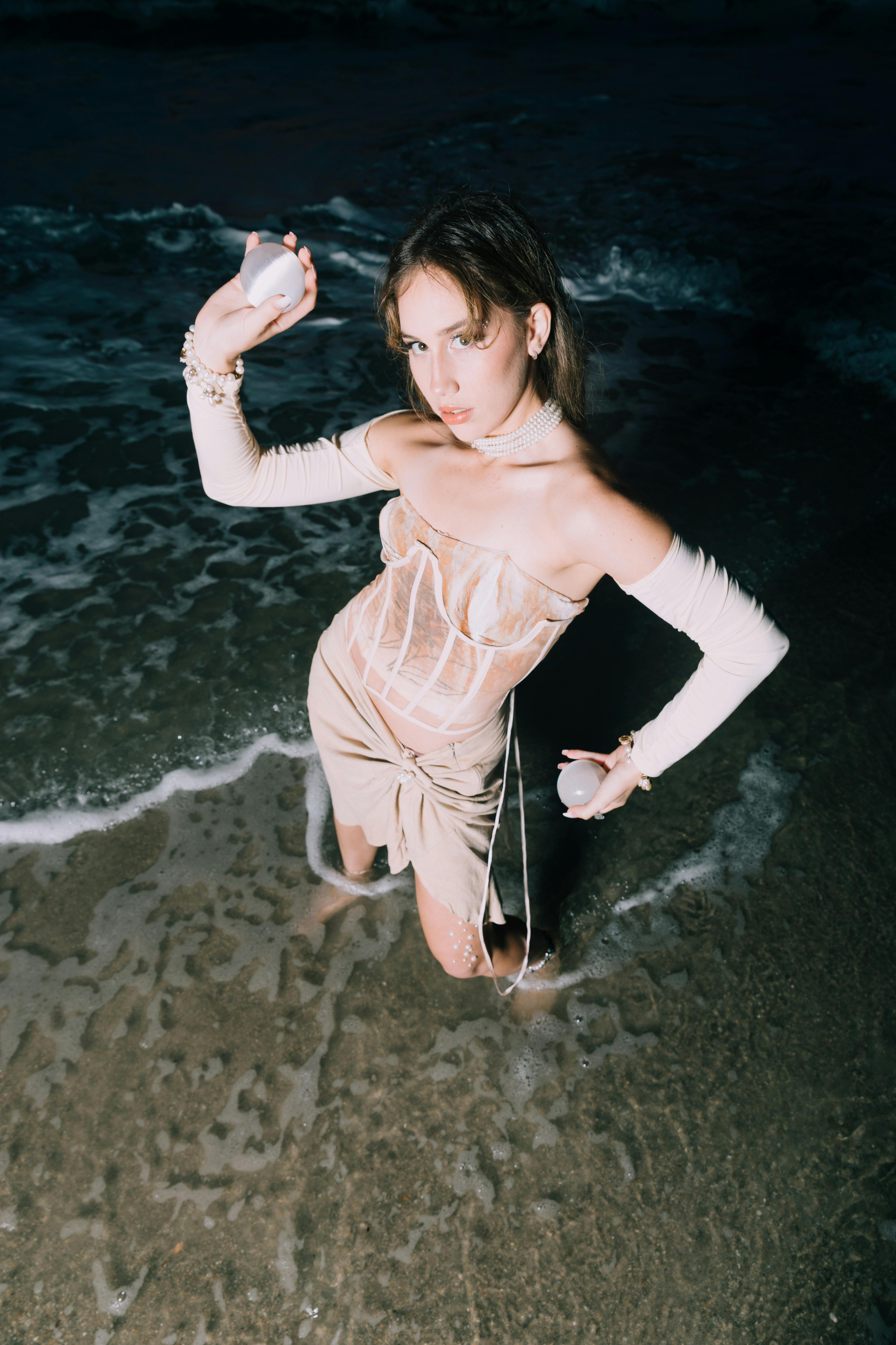 少妇在晚上，身着米色礼服，摆放在海滩上，展现出优雅与时尚