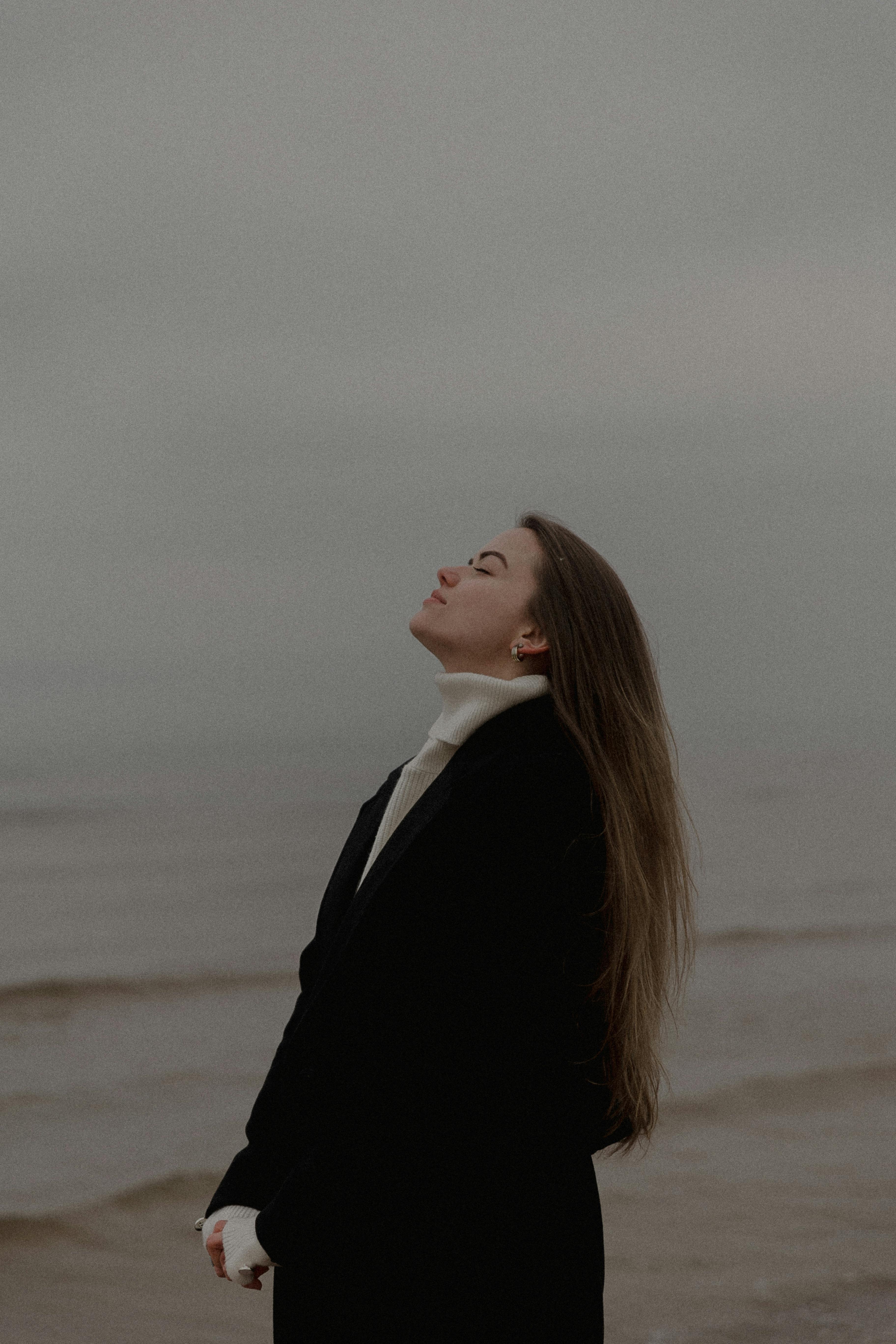 Portrait of a woman enjoying the tranquility of a misty beach day.