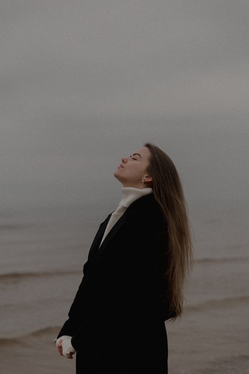Free Portrait of a woman enjoying the tranquility of a misty beach day. Stock Photo