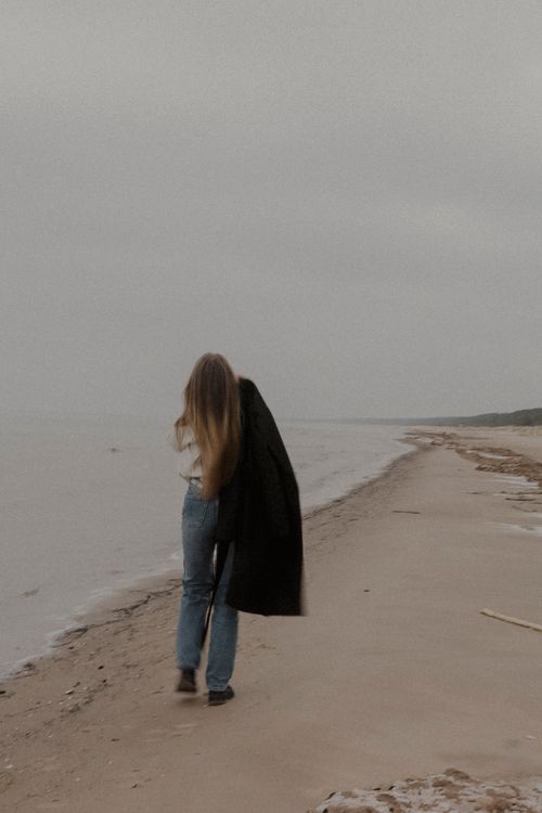 Free A woman strolls on a deserted beach, capturing solitude and tranquility. Stock Photo