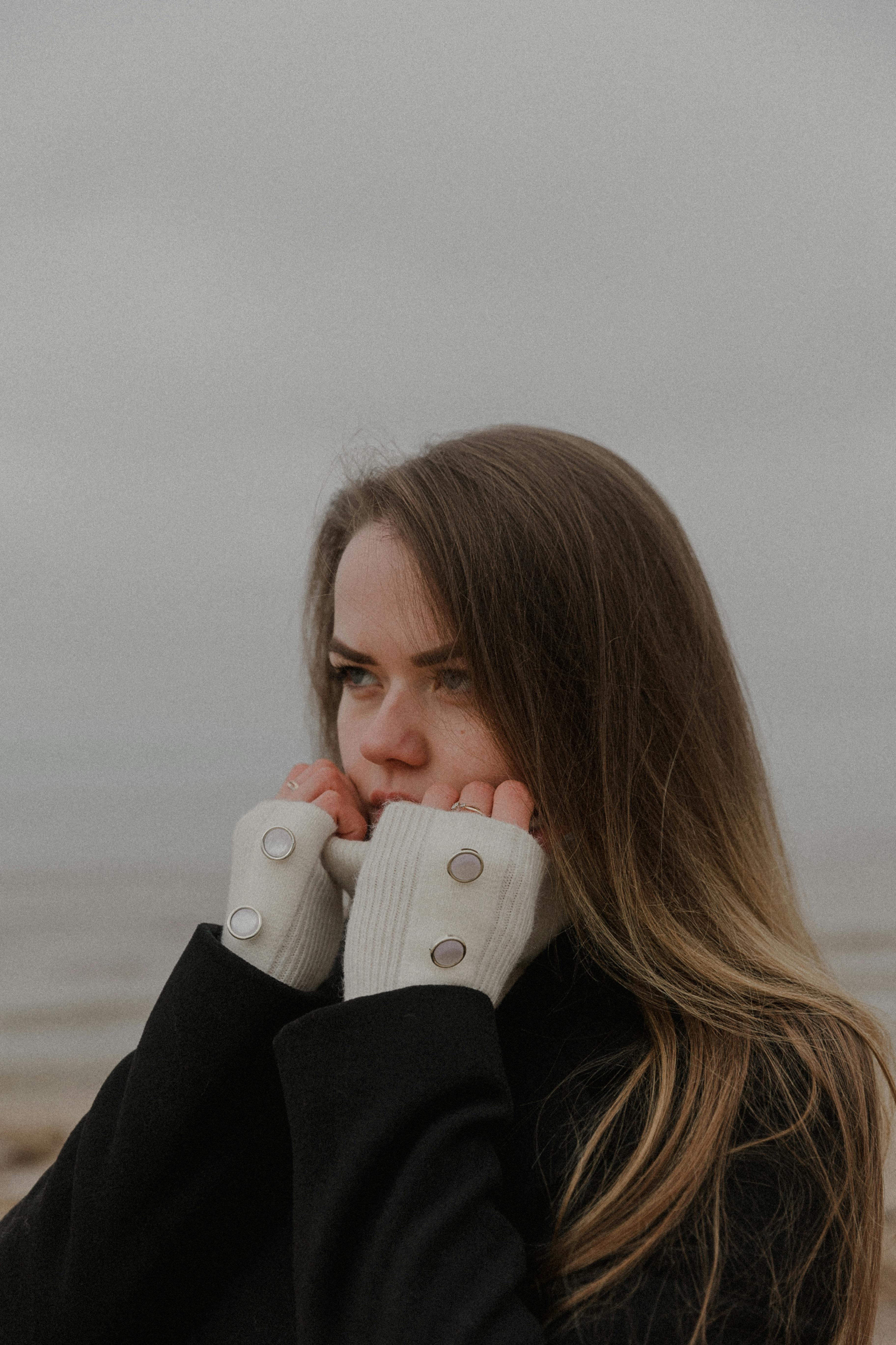 A woman stands outdoors in winter attire, exuding a thoughtful and contemplative mood.