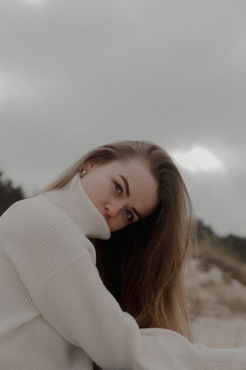 Free Portrait of a woman in a sweater, outdoors, capturing a moody autumn feel. Stock Photo