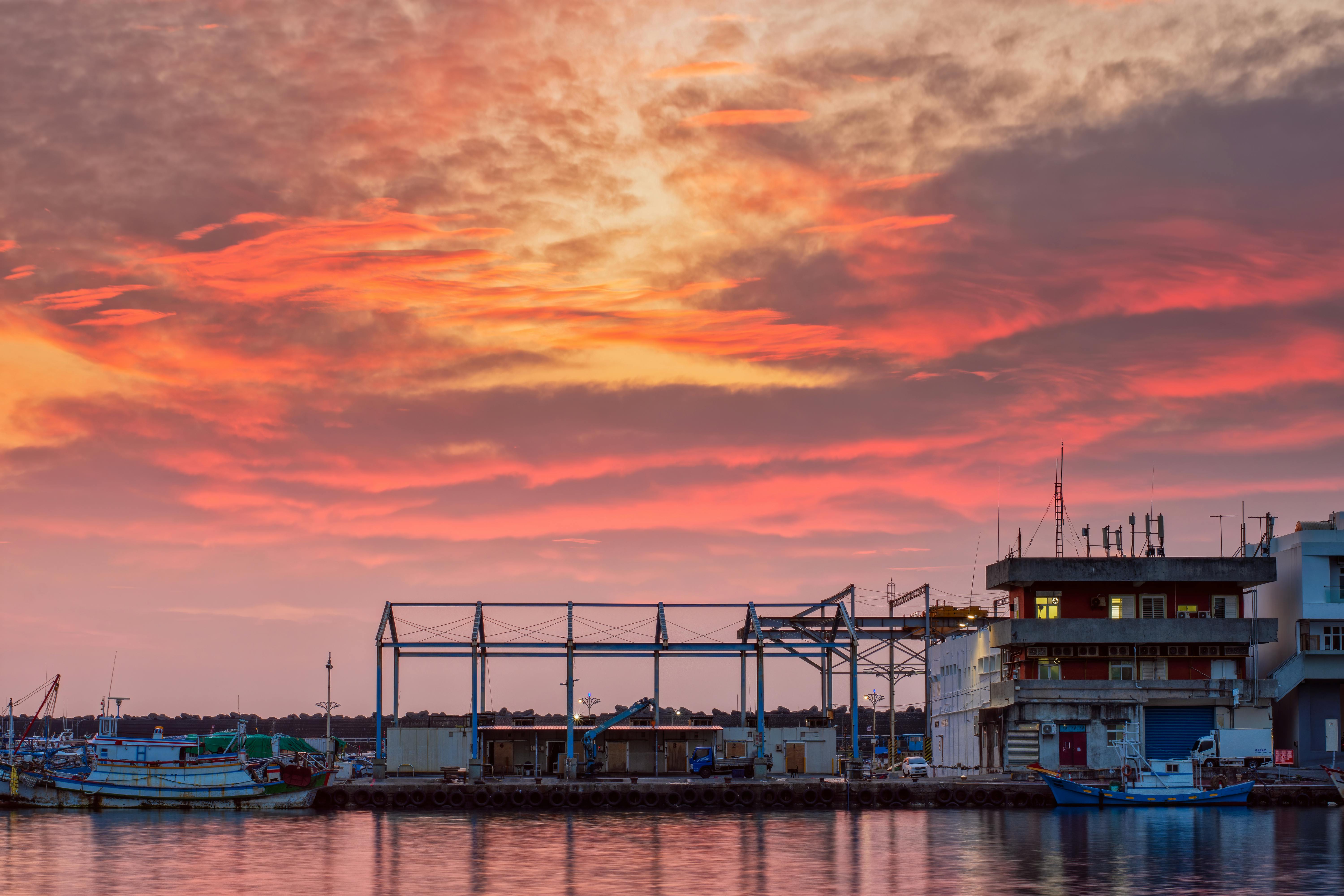 Vivid sunset over a Taiwanese harbor with vibrant hues reflecting on the water