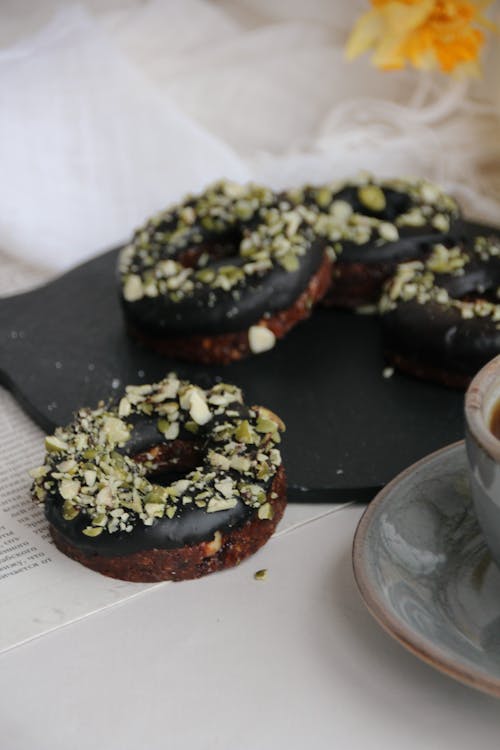 Chocolate Donuts Sprinkled with Nuts on Black Plate