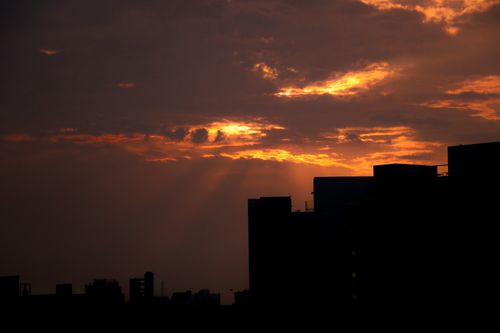 Free Silhouetted urban skyline under a dramatic sunset sky filled with clouds. Stock Photo