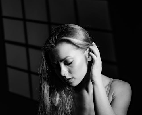 Black and White Photo of a Young Woman Tucking Hair behind Her Ear