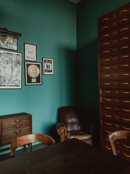 Explore this vintage-style office featuring teal walls, wooden furniture, and retro decor, exuding a classic charm.