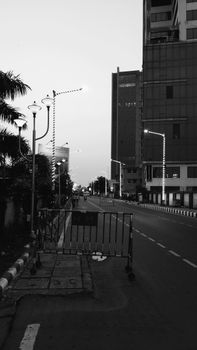A serene urban street scene at dawn, featuring tall buildings and street lights in black and white.